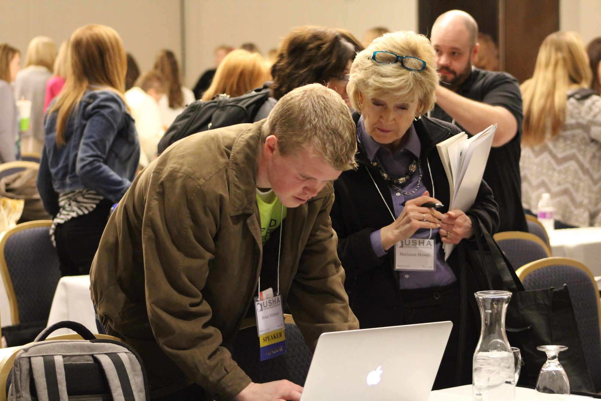 Brian demonstrating AAC functions on a computer to people at a conference.